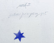 Eine handgeschriebene Notiz „Farben für ein junges Mädchen“ mit einer Signatur ziert die weiße Leinwand. Darunter leuchtet hell ein blauer achtzackiger Stern auf diesem Unikat namens „Chromatische Konstellation“ von Heinz Mack, erhältlich bei Geuer & Geuer.