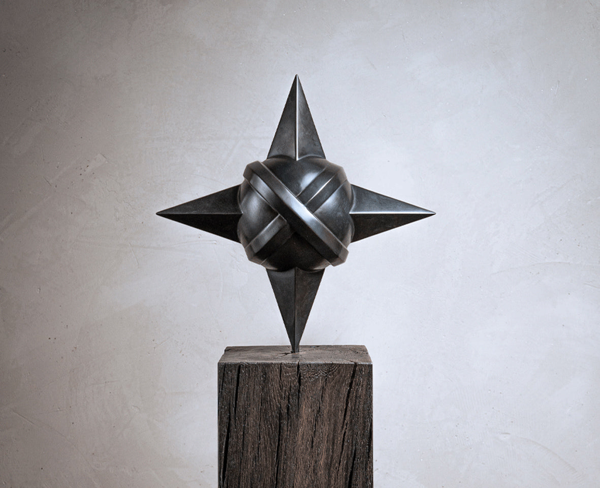 Detailaufnahme des Kunstwerks 'Sacred Planet' von Rita Sabo – dunkle Metallskulptur mit geometrischen Formen auf Holzsockel.